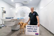 MRI-naming, dog standing beside a male holding a board